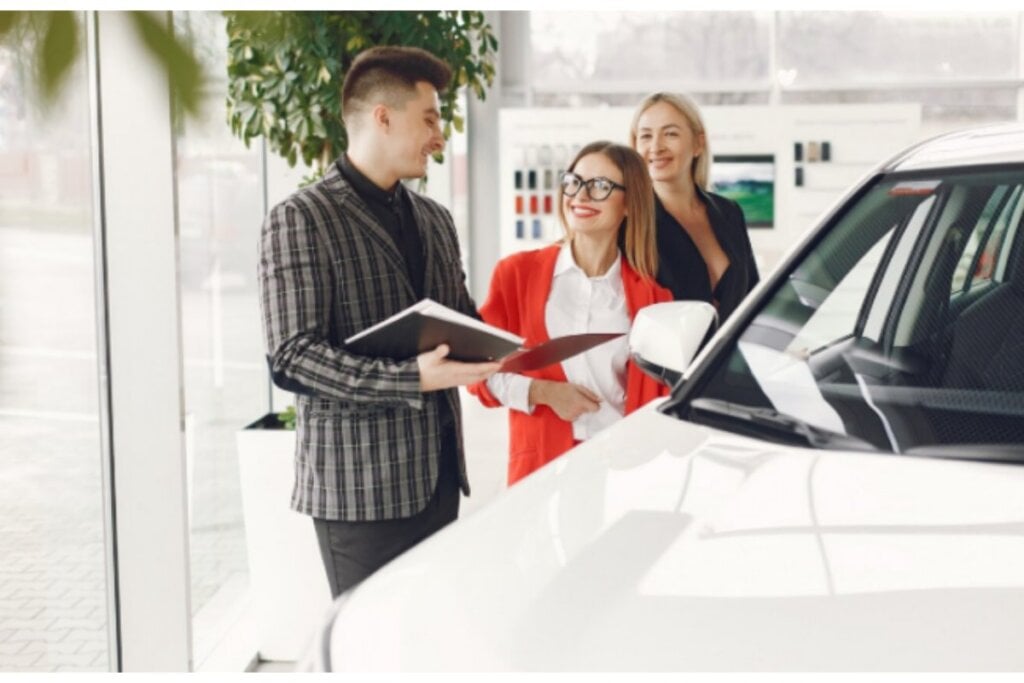 Mujer recibiendo llaves de auto frente a concesionario