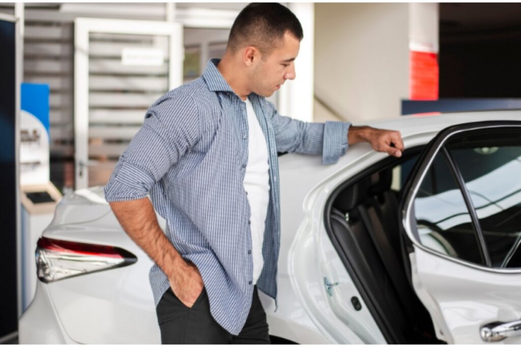 Hombre inspeccionando auto blanco en sala de ventas