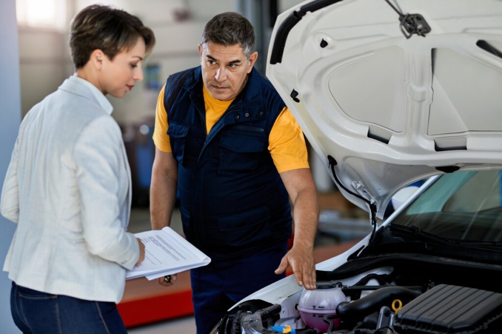 Mecánico explicando el estado del motor a cliente en taller