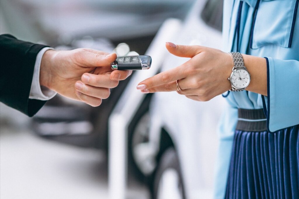 Mano de vendedor entregando llaves de coche a clienta