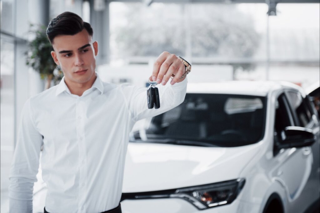 Joven sosteniendo llaves frente a un coche blanco