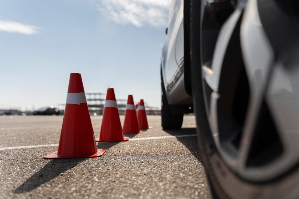 Conos naranjas alineados junto a un coche en pista de prácticas
