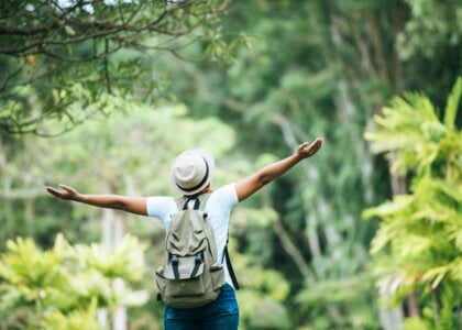 Young happy woman with backpack raising hand enjoy with nature. Woman travel concept.