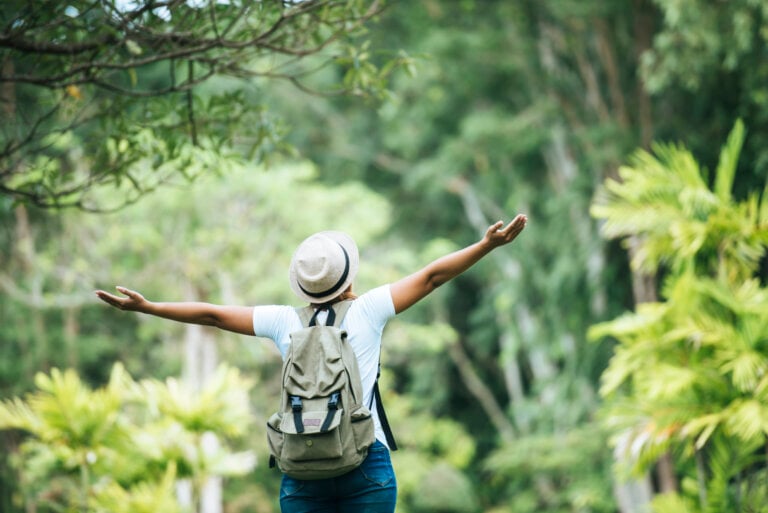 Young happy woman with backpack raising hand enjoy with nature. Woman travel concept.
